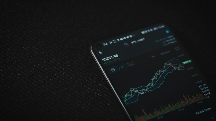 A phone with a candlestick chart on the screen