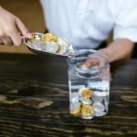 Someone pouring physical crypto coins into a jar