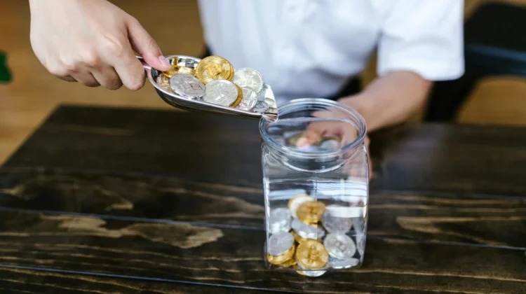 Someone pouring physical crypto coins into a jar